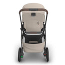 Uppababy Kona Stroller in Ada (Sandstone Mélange) with a brown handle, storage basket, and sleek design, viewed from the back.