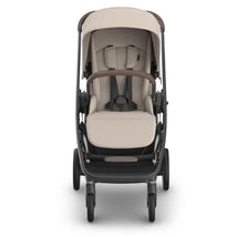 Uppababy Kona Stroller with beige seating and brown accents, featuring a harness and adjustable canopy, designed for infants.