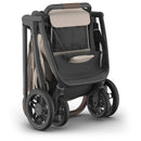 Uppababy Kona Stroller featuring a sandstone mélange fabric with a streamlined design and four wheels for easy mobility.