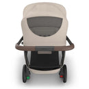 Uppababy Kona stroller with a tan canopy, brown handlebar, and visible safety harness.