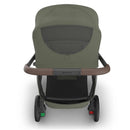 Uppababy Kona stroller in Meadow Green, featuring a mesh back and a brown handlebar, with visible wheels and frame.