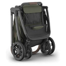 Uppababy Kona Stroller in Meadow Green, featuring a folded design with a spacious seat, adjustable handle, and sleek wheels.