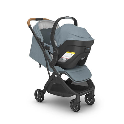 Uppababy Mesa V3 infant car seat in Stone Blue, attached to a stroller with a grey fabric seat and a brown handle.