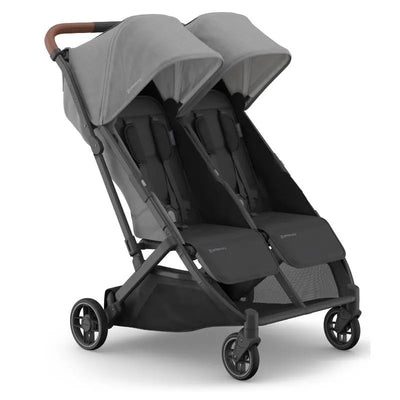 Compact double stroller with a charcoal mélange fabric, carbon frame, and saddle leather accents, designed for two children.