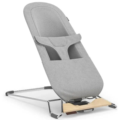 Uppababy Mira 2-In-1 Bouncer & Seat in Stella color, featuring a sleek gray fabric cover and a wooden base.