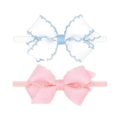 Two mini grosgrain bows, one white with blue stitching and one light pink, placed on white background.