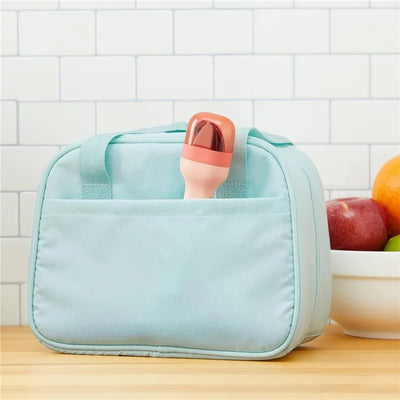 ZOKU Pocket Utensil Set in peach color partially visible in a mint green bag on a kitchen counter.