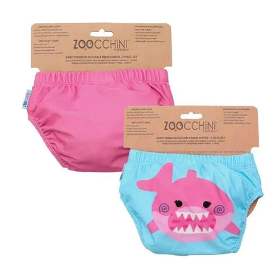 Two-pack set of Zoocchini baby swim diapers: one pink and one light blue with a shark design. Eco-friendly and reusable.