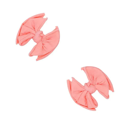 Two coral Baby Bling Bows fabric hair clips for babies on a white background