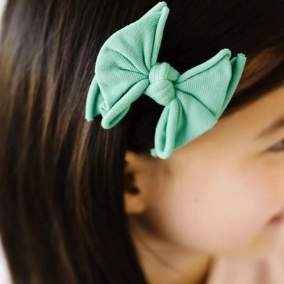 Mint green Baby Bling Bows fabric hair clip on a child's dark hair