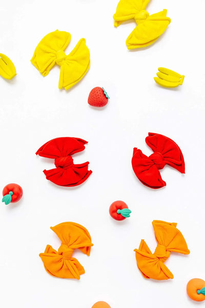 Baby Bling Bows colorful fabric hair clips in yellow, red, and orange on a white background.