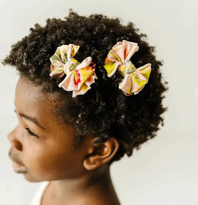 Baby Bling Bows 2PK printed baby fabric clips in floral patterns on a child's curly hair.